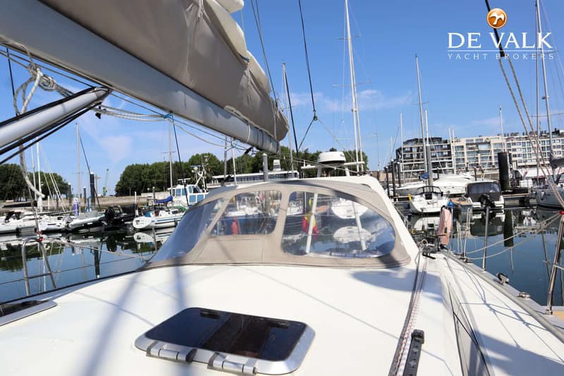 Een witte zeilboot met een beige buiskap en een luik op het dek, liggend in een haven met andere boten. — Berckemeyer 43