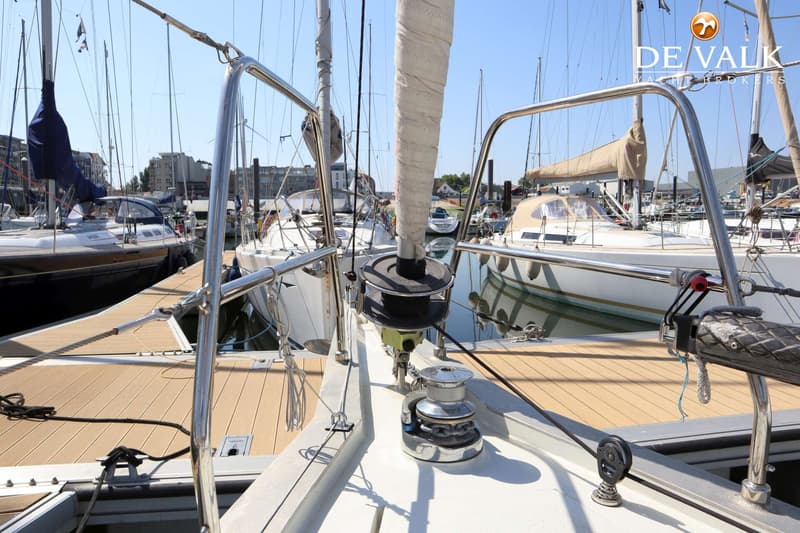 Een boot ligt aangemeerd in een haven, met een opgerold zeil en een lier op het voordek. — Berckemeyer 43