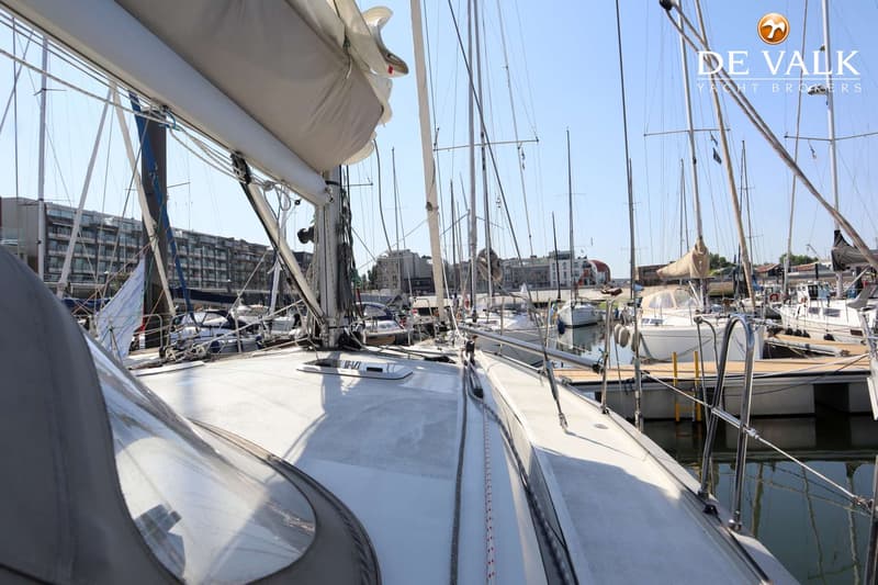 Een dek van een zeilboot met een grijze buiskap, omringd door andere zeilboten in een haven. — Berckemeyer 43