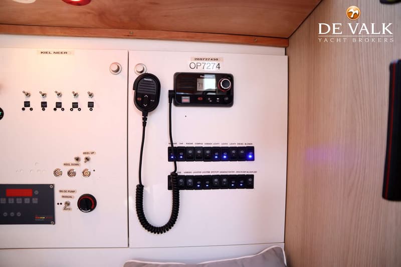 Een wit bedieningspaneel met schakelaars, een Raymarine marifoon en een Raymarine display is zichtbaar.