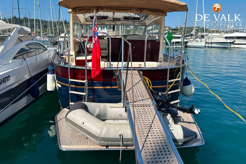 Een boot met een bijboot op het zwemplateau, een loopplank, een vlag en een buitenboordmotor. — Apreamare 12 Cabinato
