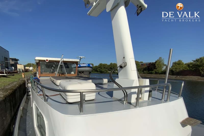Een witte boot met een grijs dek en een houten stuurhuis, liggend aan een kade met bomen op de achtergrond. — Luxe motor 22 m