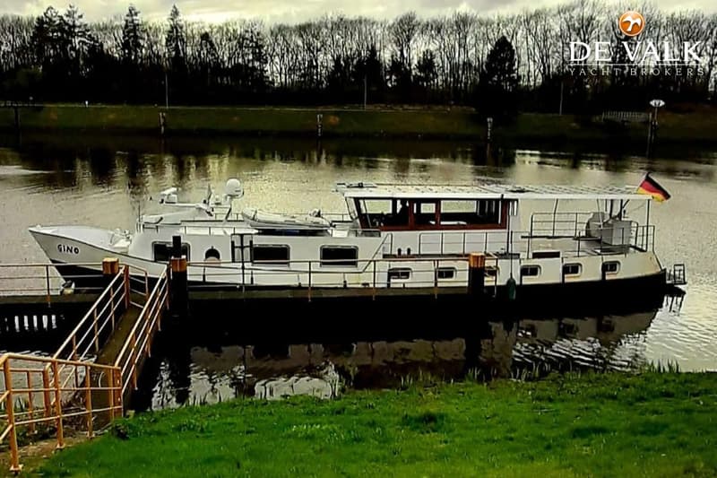 Een witte motorboot met de naam "GINO" ligt aangemeerd aan een steiger, met een Duitse vlag aan de achtersteven.