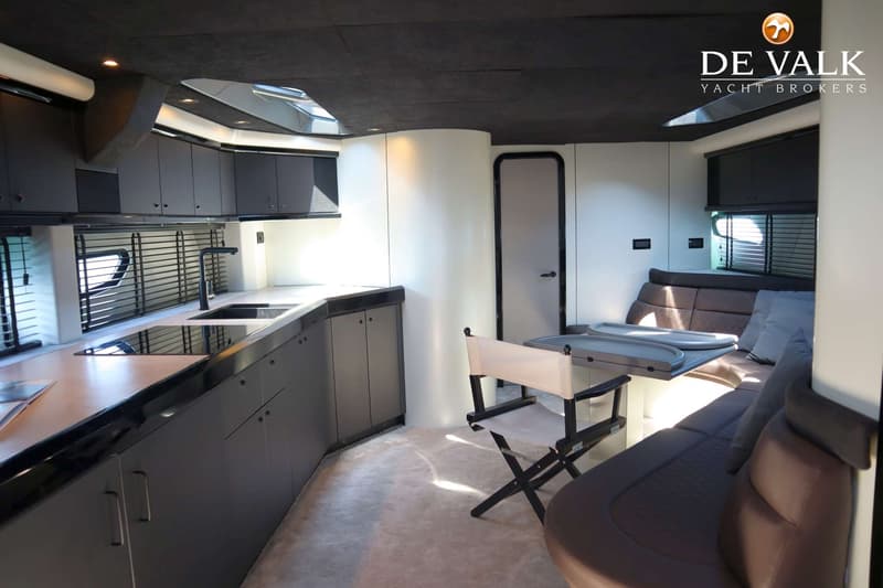 Een interieur van een boot met een keukenblok, een zitbank, een klapstoel en een tafel. — Sunseeker Predator 56
