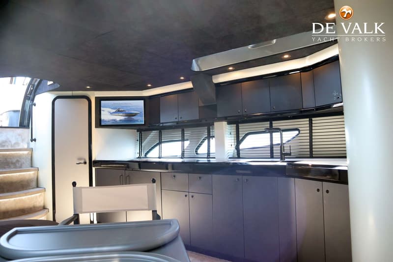 Een interieur van een boot met een keukenblok, een televisie, een trap en een stoel. — Sunseeker Predator 56