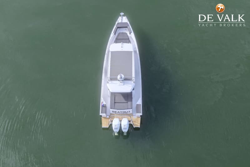 Een witte motorboot met twee buitenboordmotoren en de naam "SEAYOU2 WILLEMSTAD" op de spiegel, drijvend op groen water.