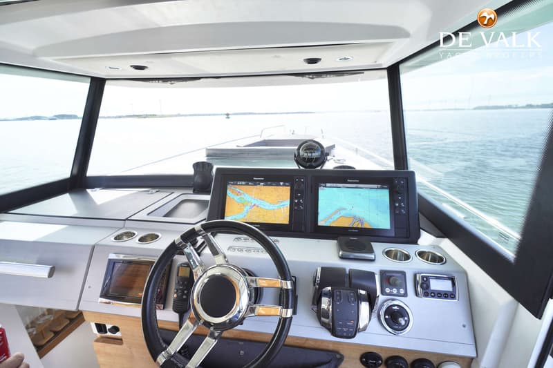 De foto toont een stuurstand met twee Raymarine navigatieschermen, een stuurwiel, gashendels en diverse bedieningspanelen.