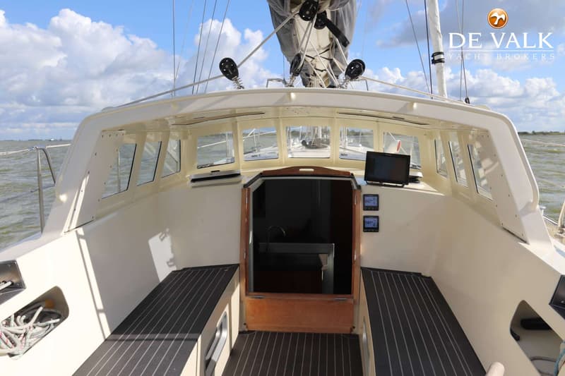 De foto toont het dek van een zeilboot met een kajuitingang, zitbanken en navigatieschermen. — Aluyacht 49