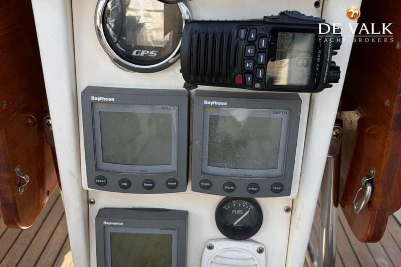 De foto toont een detail van het dashboard van een boot met diverse navigatie-instrumenten en een marifoon.