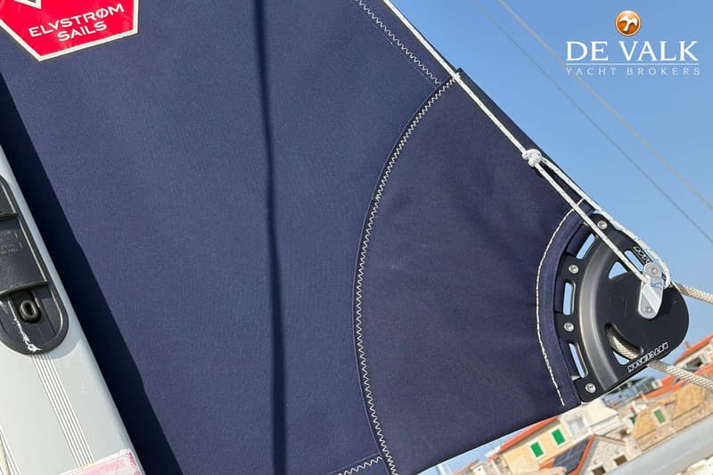 Een donkerblauw zeil met witte stiksels en een rood "Elvstrøm Sails" logo is zichtbaar.