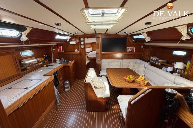 De foto toont het interieur van een boot met een kombuis, salon en een doorgang naar een slaapcabine. — Bavaria 47 Cruiser
