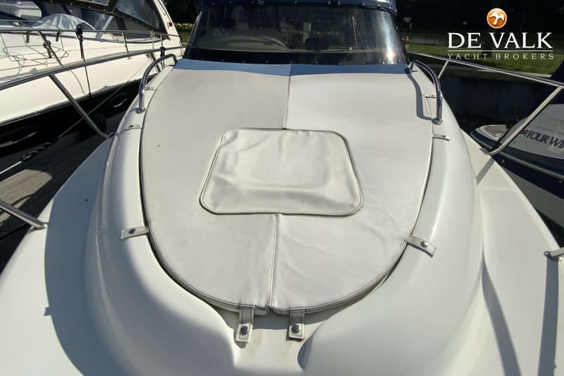 De foto toont de boeg van een witte boot met een wit kussen en een voorruit, met een logo van "DE VALK YACHT BROKERS"…