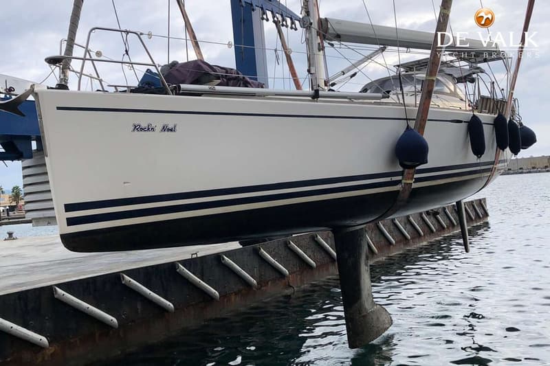 Een witte boot met een grijze buiskap en een transparant voorraam, liggend aan een kade met gebouwen op de achtergrond.