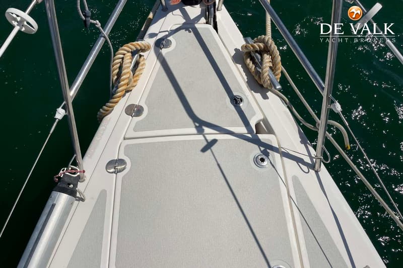 Een bovenaanzicht van de boeg van een witte boot met grijze antislipmatten, omringd door donkergroen water. — Arcona 430