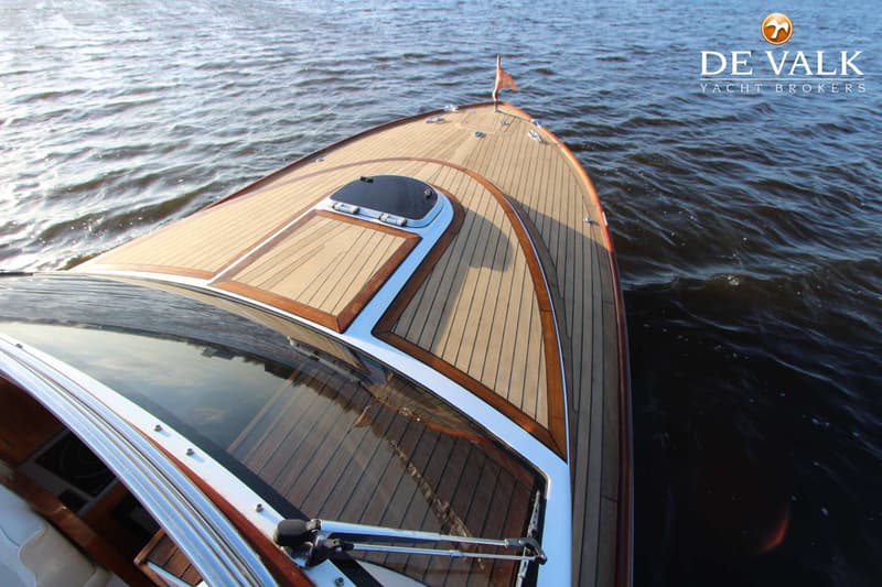 De foto toont de boeg van een boot met een houten dek en een voorruit, varend op water. — Long Island 33 Runabout