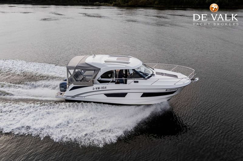 Een witte motorboot met de naam "BARISTA" en registratienummer "5-YH-254" vaart over water, spuitend schuim op.