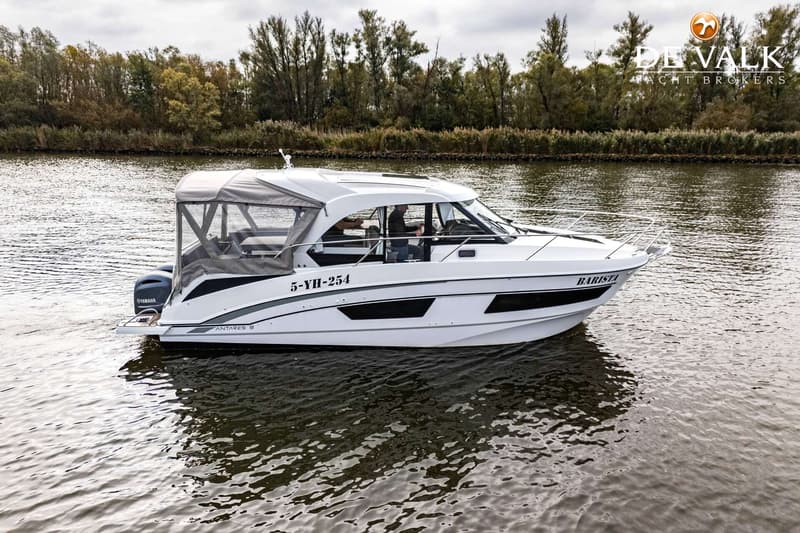Een witte motorboot met een grijze kap vaart op het water, met bomen op de achtergrond. — Beneteau Antares Serie 9