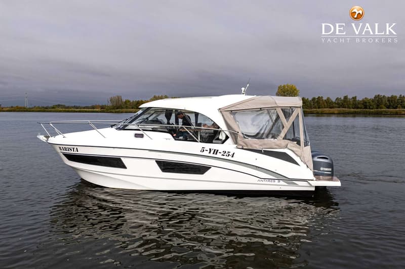 Een witte motorboot met een grijze kap en een buitenboordmotor vaart op rustig water onder een bewolkte lucht.
