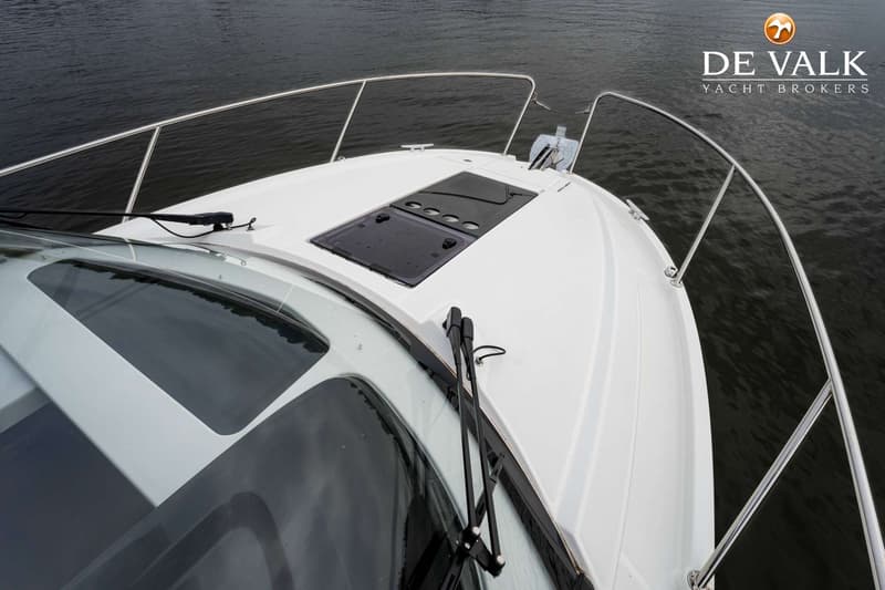 De voorkant van een witte boot met een reling, ramen, ruitenwissers en een luik is zichtbaar. — Beneteau Antares Serie 9