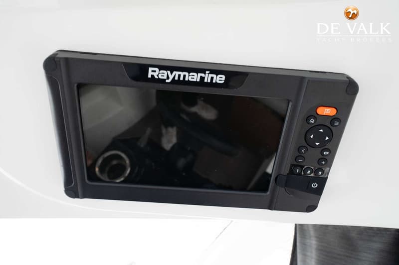 Een zwarte Raymarine kaartplotter met knoppen en een scherm is gemonteerd op een wit oppervlak.