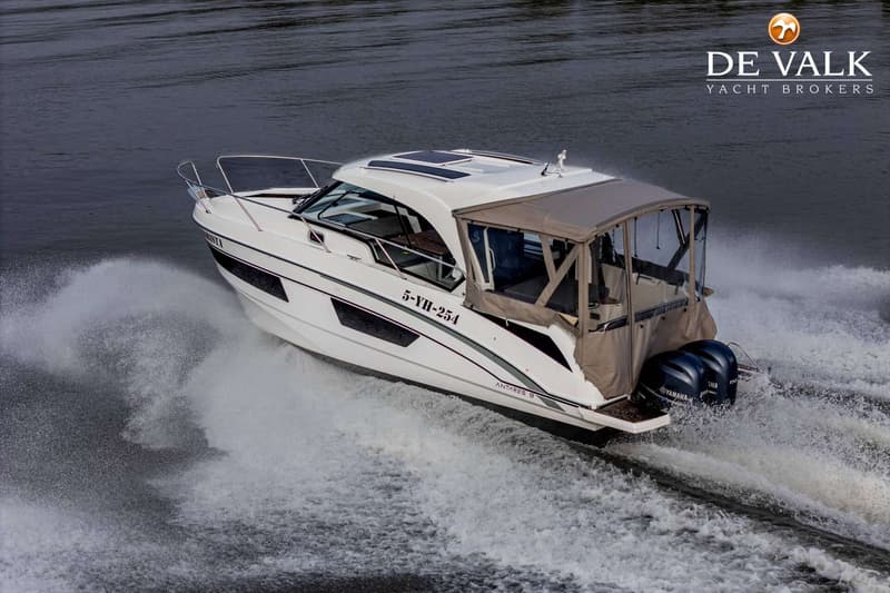 Een witte motorboot met een beige cabriokap en twee Yamaha buitenboordmotoren vaart over donker water.