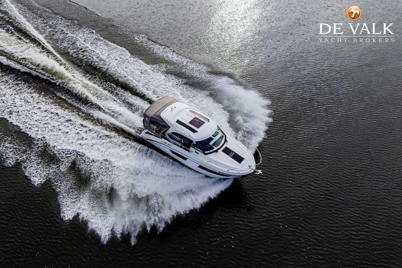 Een witte motorboot vaart over donker water en laat een spoor van schuim en golven achter. — Beneteau Antares Serie 9