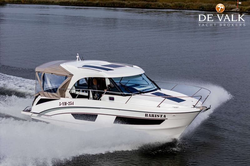 Een witte motorboot met de naam "BARISTA" en registratienummer "5-YH-254" vaart over water, met een beige biminitop.