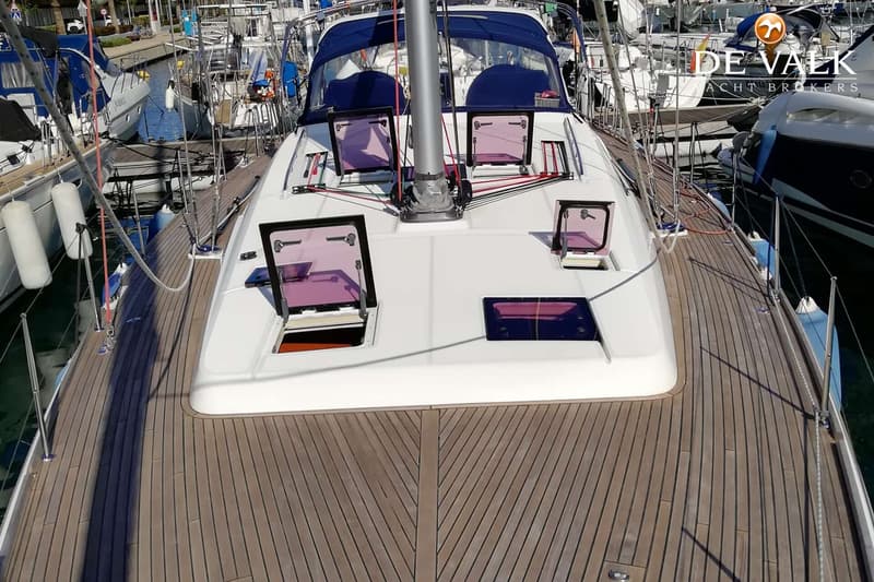 Een bovenaanzicht van het dek van een zeilboot met houten planken, luiken en een mast. — Beneteau Oceanis 58
