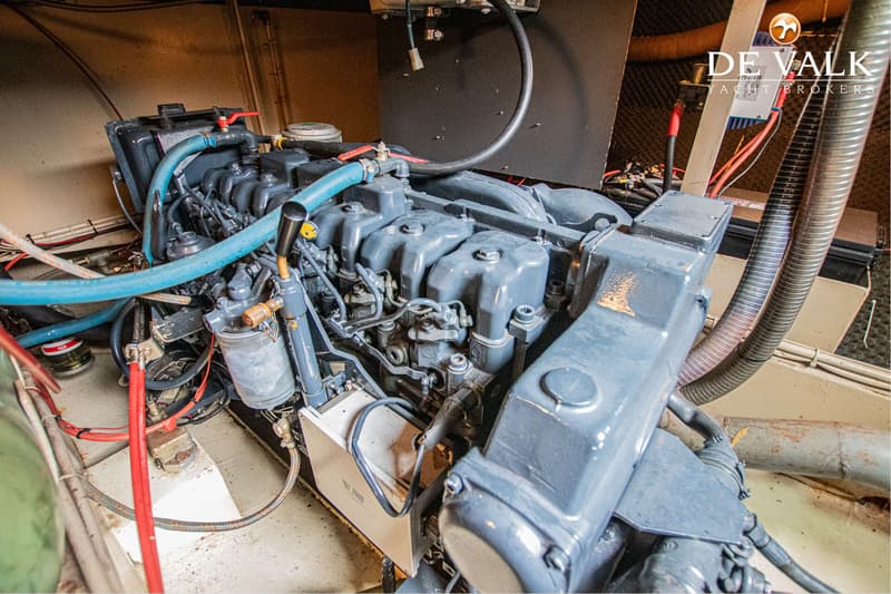 Een close-up van een scheepsmotor met diverse slangen, kabels en filters in een motorruimte.