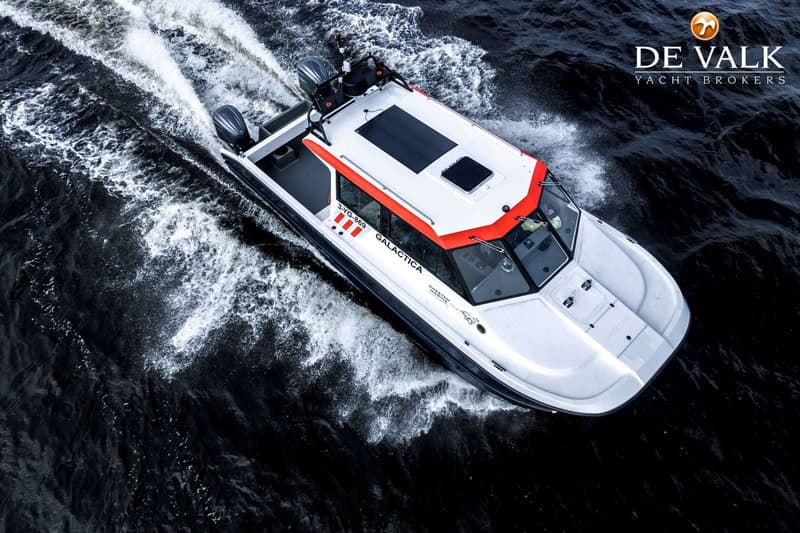 Een witte boot met oranje accenten en de naam "GALACTICA" vaart op donker water, met twee buitenboordmotoren zichtbaar.