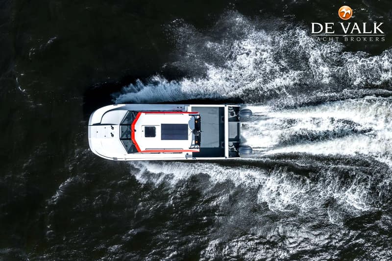 Een witte boot met oranje accenten en twee buitenboordmotoren vaart door donker water en laat een wit kielzog achter.