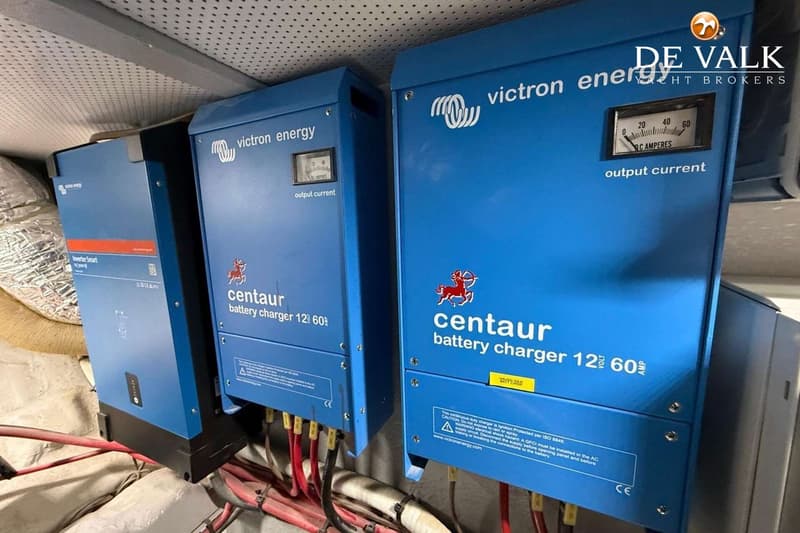Drie blauwe Victron Energy apparaten, waaronder twee Centaur acculaders, zijn gemonteerd met bedrading eronder.