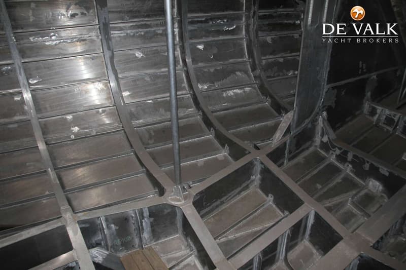 De foto toont de binnenkant van een metalen scheepsromp in aanbouw, met zichtbare spanten en verstevigingen.