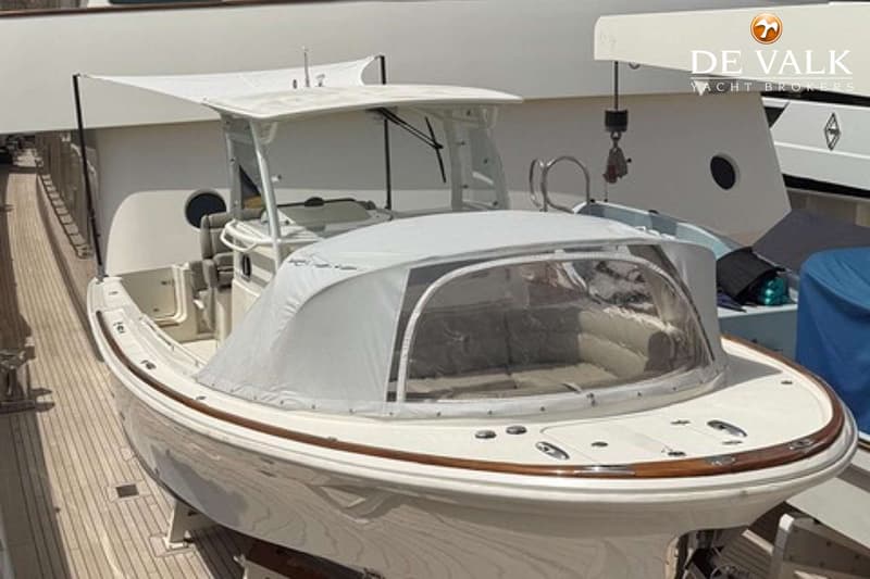 Een witte boot met een houten rand en een witte kap met doorzichtige ramen staat op een houten dek. — Hunt Surfhunter 33