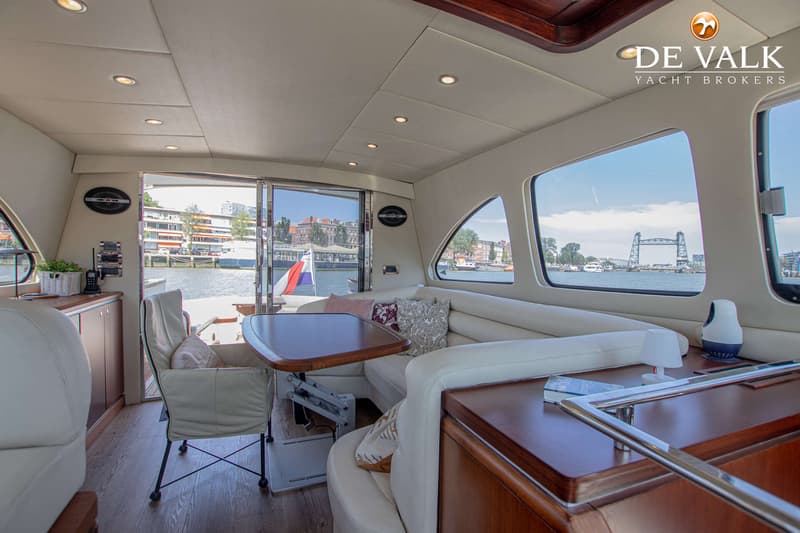 Een interieur van een boot met een zithoek, een tafel en uitzicht op water en een brug. — Rapsody 55