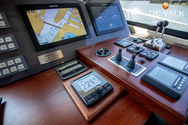 Een close-up van een stuurstand met diverse navigatie- en bedieningspanelen, waaronder twee Raymarine schermen.