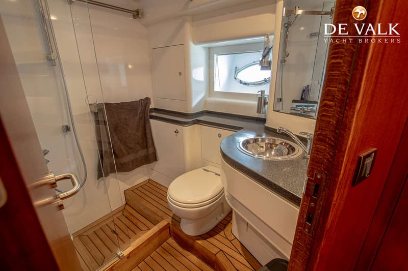 De foto toont een badkamer met een douche, toilet, wastafel en een patrijspoort.