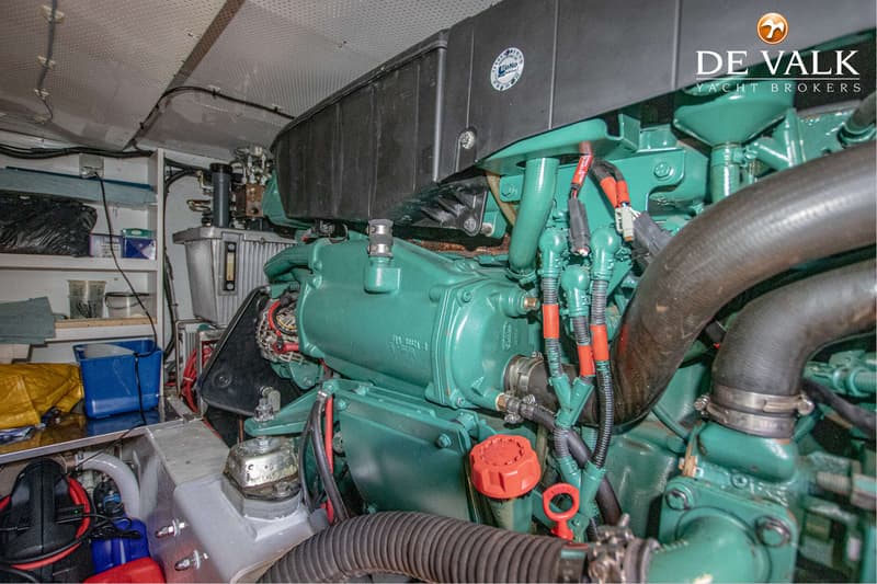 Een groene scheepsmotor met diverse slangen en kabels is zichtbaar in een motorruimte.