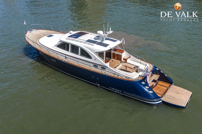 Een blauw-witte motorboot met houten dek en een uitschuifbaar zwemplateau ligt in het water. — Rapsody 55