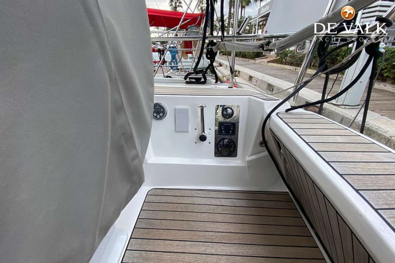 De foto toont een deel van een bootkuip met een houten vloer en een wit paneel met diverse meters en bedieningselementen.