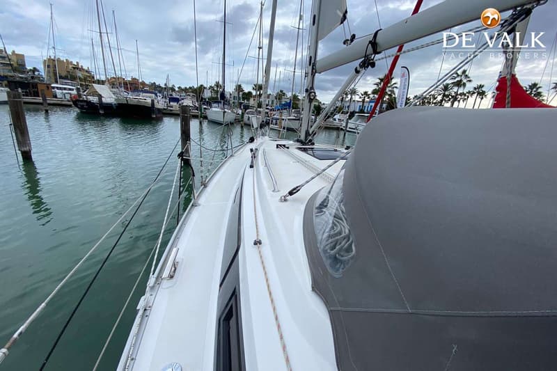 Een witte zeilboot ligt in een jachthaven met een grijze buiskap en een opgerold zeil op de giek. — Bavaria 34 Cruiser
