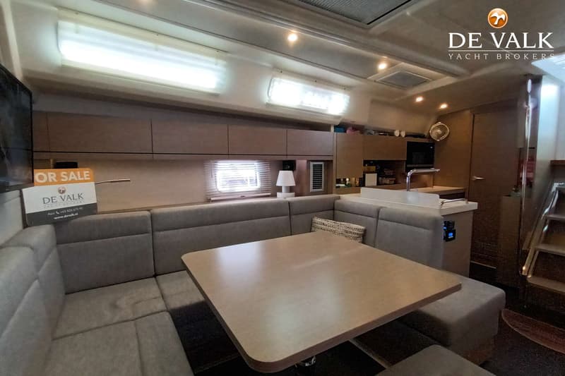 De foto toont het interieur van een boot met een U-vormige bank, een tafel en een keukenblok. — Hanse 458