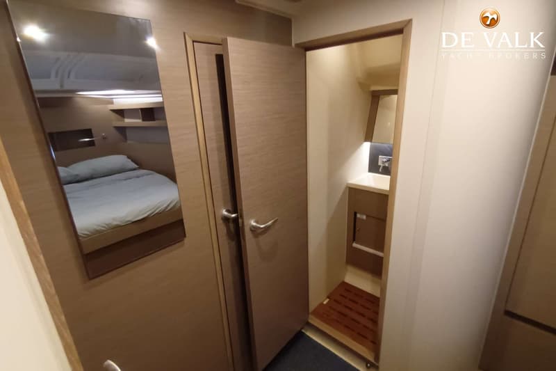Een interieurfoto toont een slaapkamer met een bed, een spiegel en een open deur naar een badkamer met wastafel en douche.