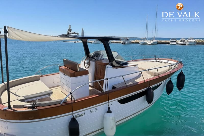 Een witte boot met houten accenten en de naam "Mimi 9.5" op de zijkant ligt in helderblauw water. — Mimi 9,5 WA