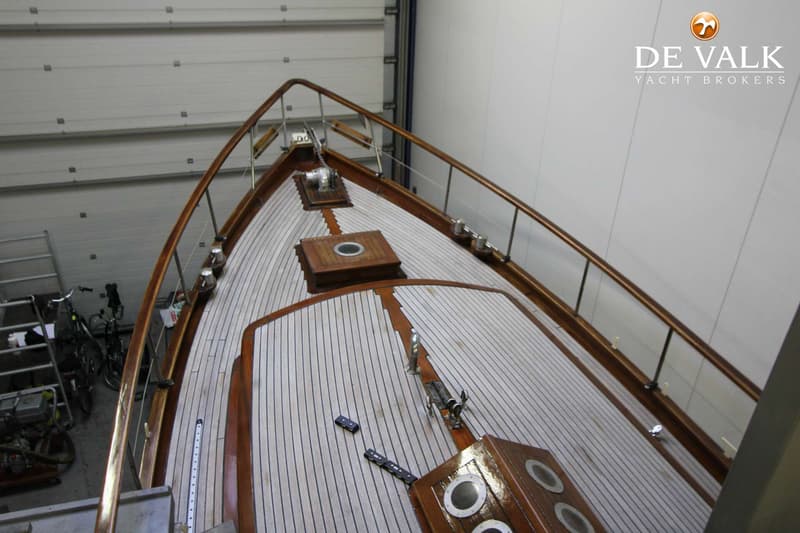 De foto toont het voordek van een boot met een houten dek en reling, gezien van bovenaf. — Danish Rose 31