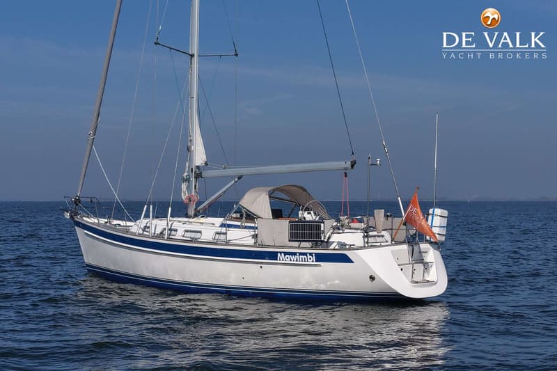 Een witte zeilboot met blauwe strepen en de naam "Mawimbi" vaart op kalm water onder een heldere lucht. — Hallberg Rassy 40