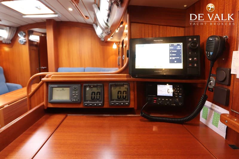 Een houten navigatiestation met diverse elektronische apparatuur, waaronder een Raymarine display, Furuno meters en een…