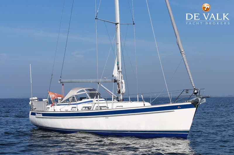 Een witte zeilboot met blauwe strepen vaart op rustig water onder een helderblauwe lucht. — Hallberg Rassy 40