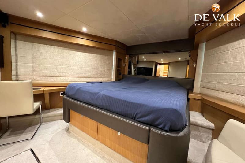Een slaapkamer met een tweepersoonsbed met blauw beddengoed, een bureau met stoel en een spiegelwand.