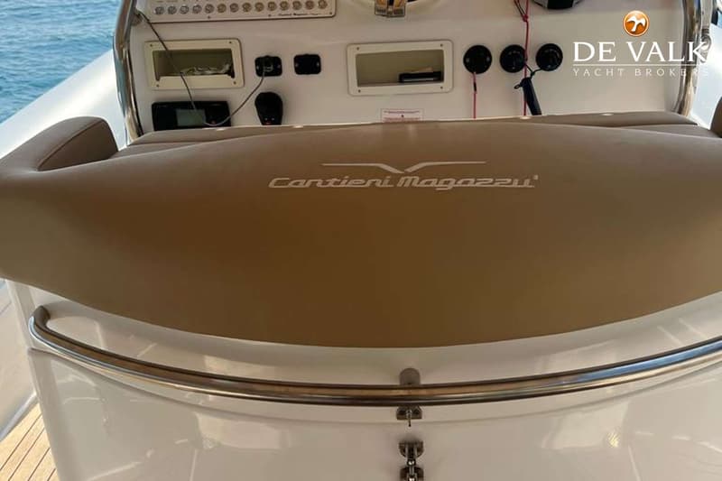 Een detailfoto van een bootinterieur met een bruine zitting met de tekst "Cantieri Magazzu" en een wit dashboard.